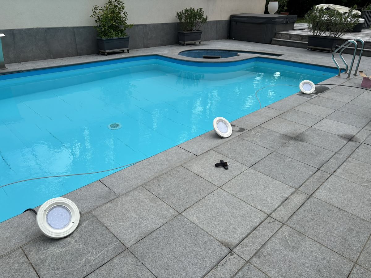 Projecteurs de piscine déposés sur la margelle pendant leur remplacement