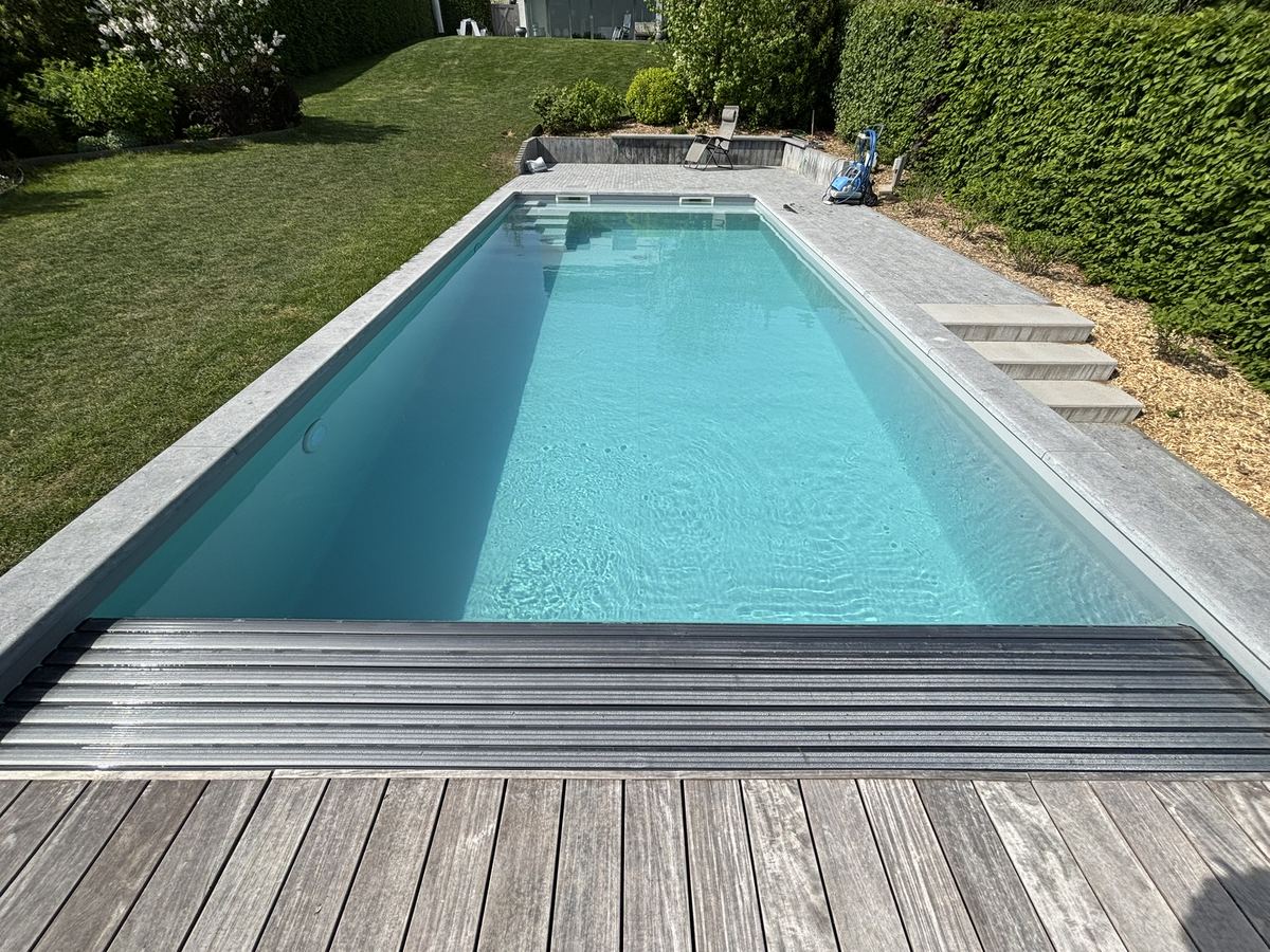 Piscine avec volet immergé et terrasse en bois, en pleine campagne